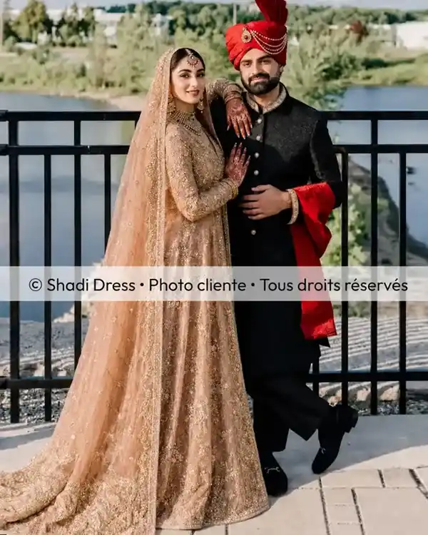 Couple de mariés, elle en robe champagne brodée et lui en sherwani noire avec turban rouge
