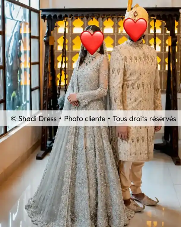Mariée en robe argentée brodée aux côtés du marié en sherwani ivoire lors de leur mariage