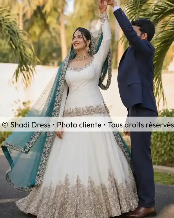 Mariée en robe blanche brodée avec dupatta vert émeraude aux côtés de son époux