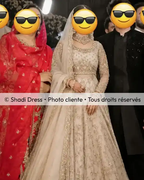 Mariée en tenue ivoire et dorée richement brodée entourée de sa famille pendant le mariage
