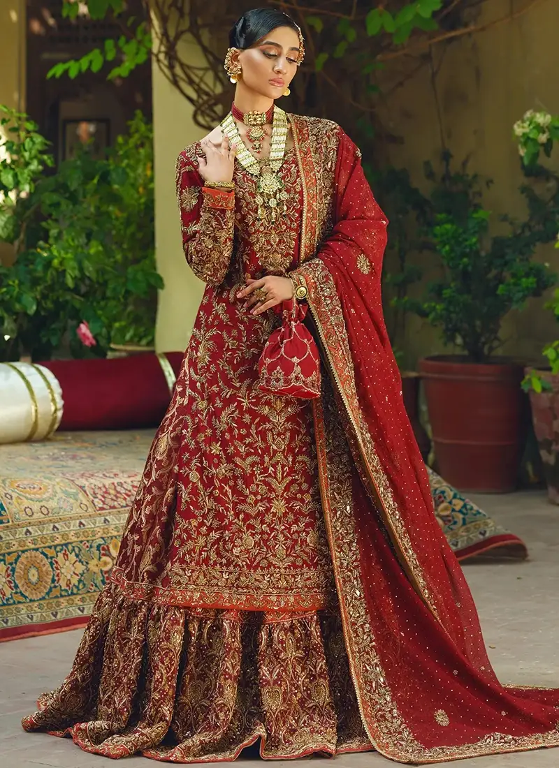 Deep red Farshi lehenga with boat-neck long shirt, gold zardozi embroidery and orange edging at the cuffs and hem