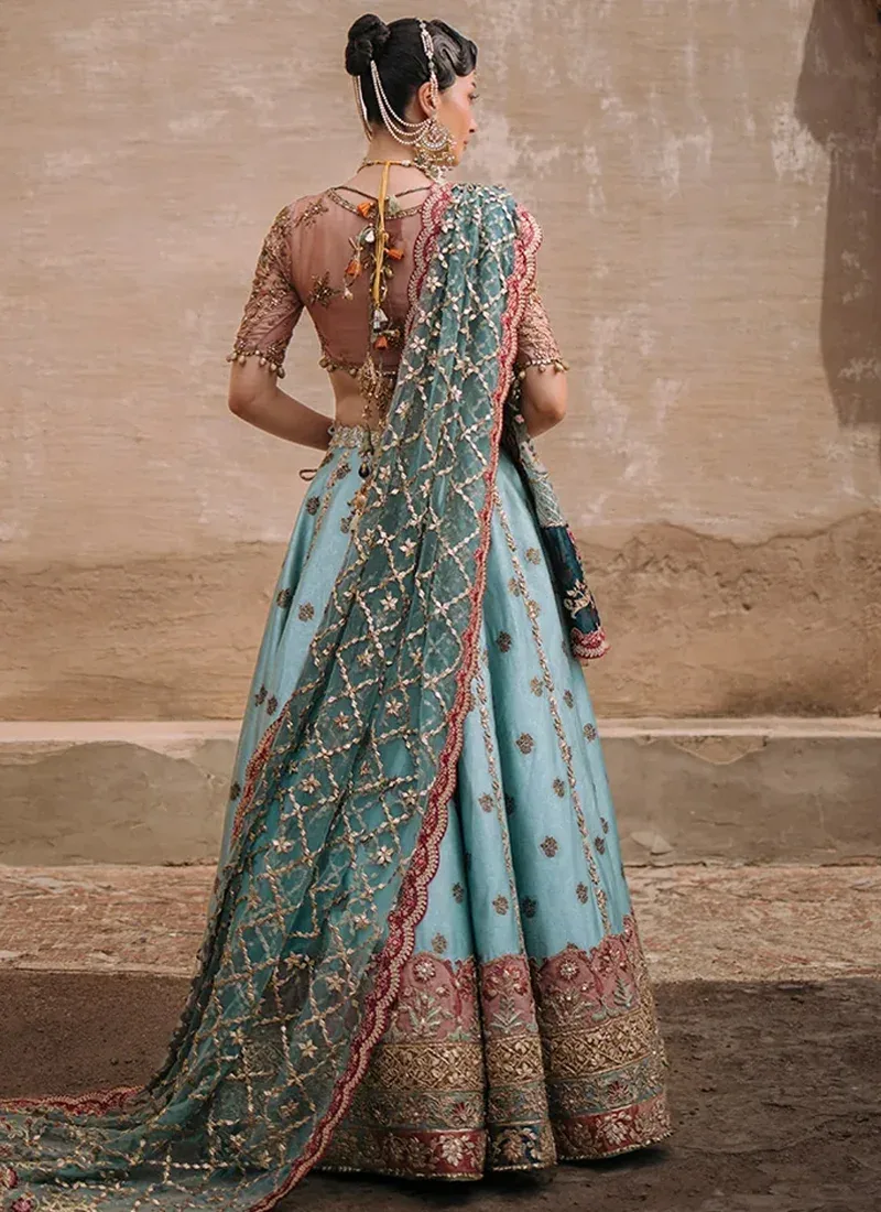 Aqua lehenga choli side view showing a scalloped pink lotus border and richly embroidered dark teal dupatta