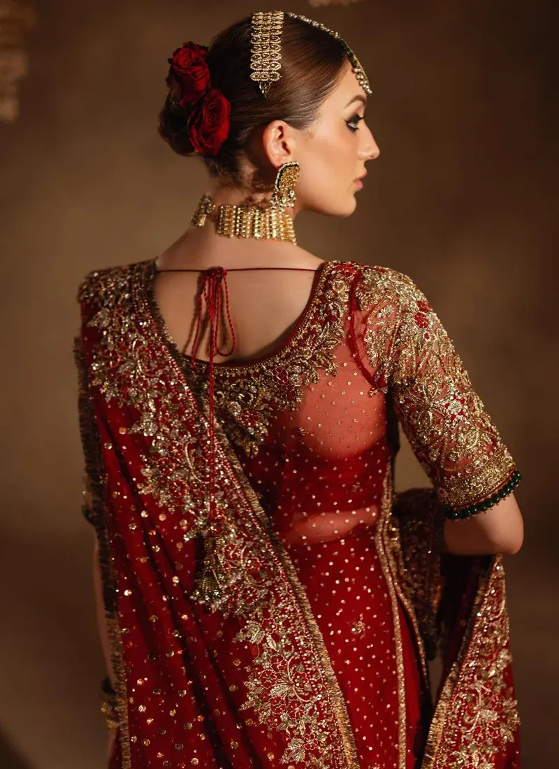 Deep red bridal farshi gharara full-length angled view with a gold floral hem and draped dupatta.