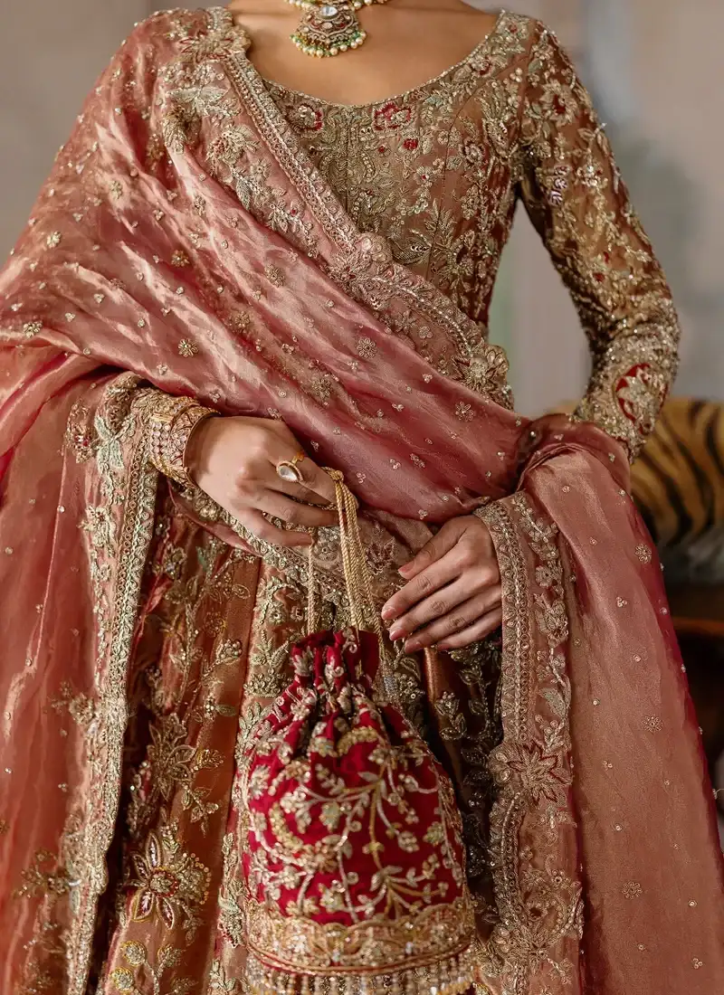 Deep red lehenga beneath a coral bridal shirt, lower front detail with scalloped gold medallion hem