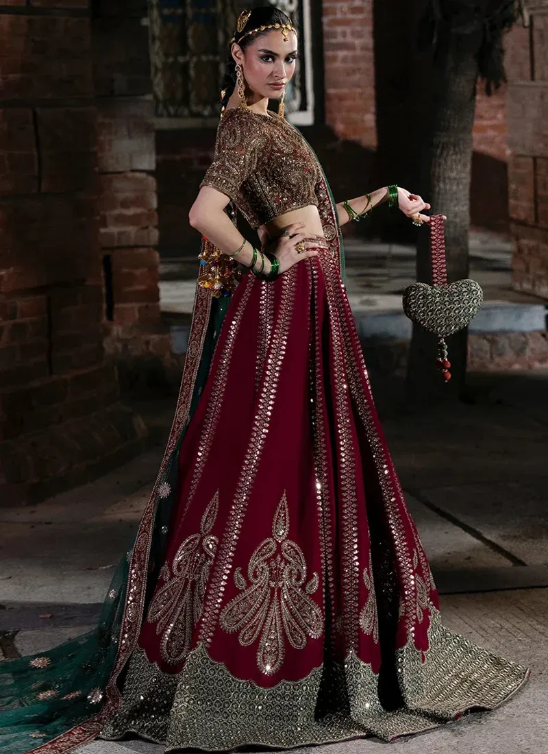 Hot pink bridal lehenga choli, side view with ornate paisley embroidery and a wide gold hem border