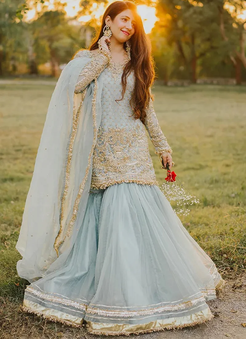 Ice Blue Walima Gharara Suit with Gold Lattice Bodice Ice blue gharara suit side view with embroidered full sleeves, gold hem borders and flowing sheer dupatta