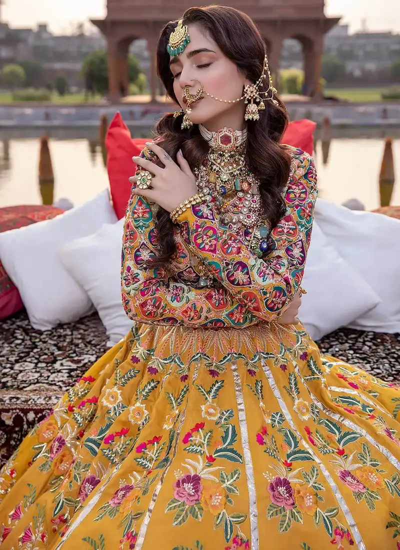 Mustard Mehndi lehenga choli full-length angled view with a teal and pink chevron embroidered hem