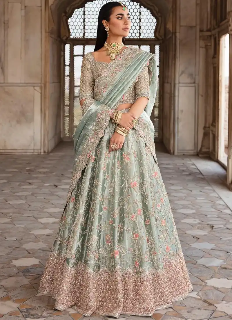 Sage green bridal lehenga choli, full front view with scattered pink floral motifs and an ornate embroidered hem.