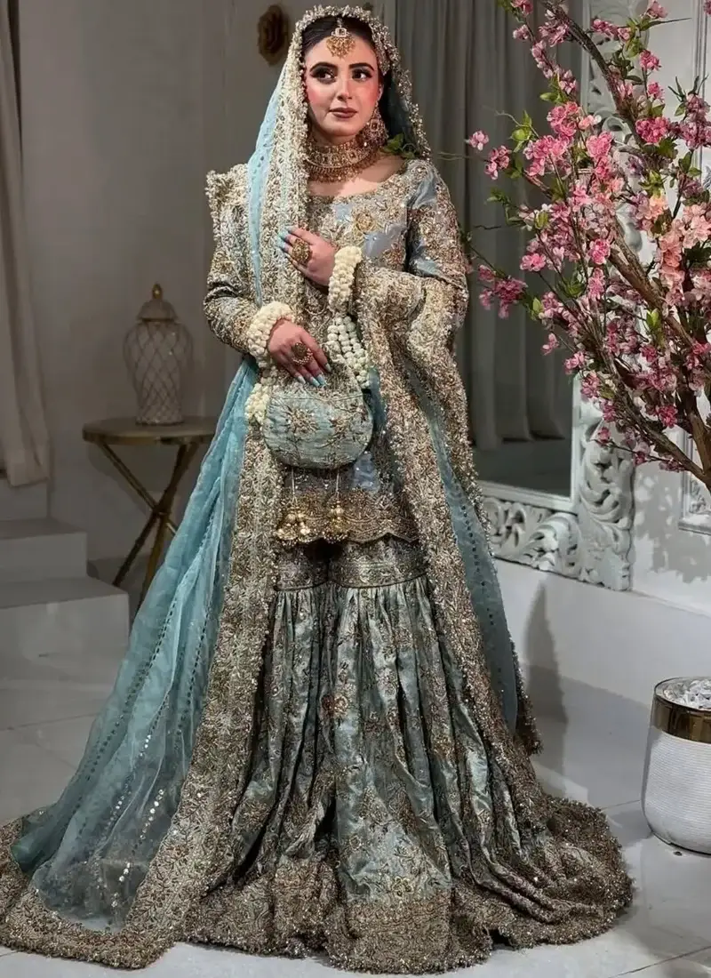 Teal Nikkah Farshi Gharara with Scalloped Zardozi Hem Dusty teal Nikkah farshi gharara seated view showing gathered flared trousers and wide gold embroidered hems