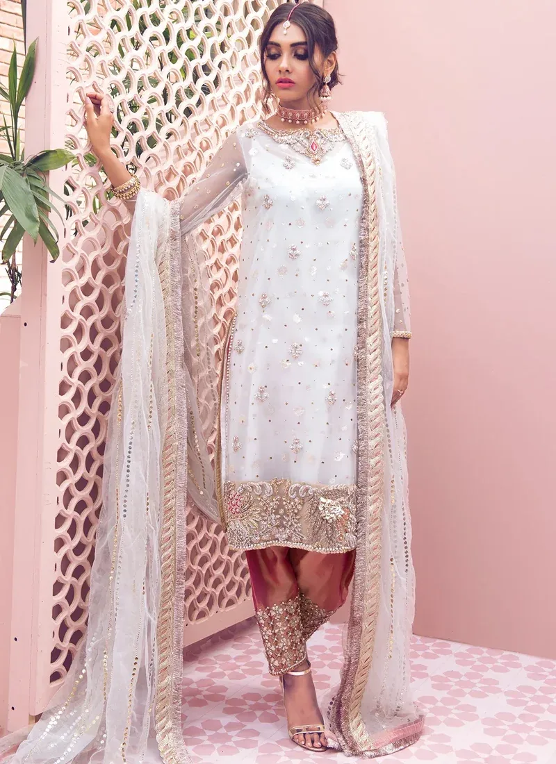 White Wedding Guest Long Shirt Trousers Suit with Coral Gota-Worked Shalwar White net kameez close-up with sheer embroidered sleeves, ornate gold floral hem and braided dupatta border